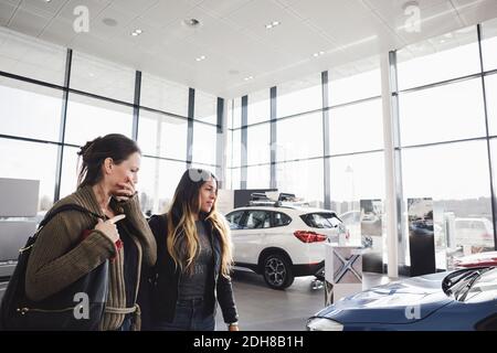 Friends looking and choosing car in showroom Stock Photo