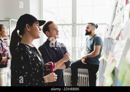 Engineers looking at whiteboard while colleagues talking in background Stock Photo