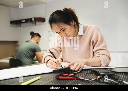 Female engineer working on paper at table in workshop Stock Photo