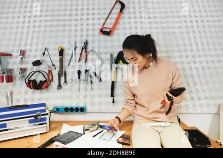 Businesswoman using smart phone while working in workshop Stock Photo