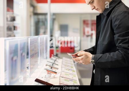 Midsection of young man using smart phone at store Stock Photo