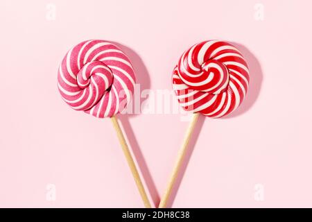 Two Lollipop candy with red, white spiral stripes on pink background. Birthday concept. Flat lay, minimal. Stock Photo