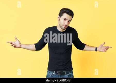 Confused young man dressed in black t-shirt have a doubt on yellow background Stock Photo