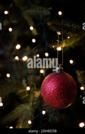 A close up of traditional Christmas tree decorations and baubles hanging on an artificial tree with twinkling fairy lights and copy space Stock Photo