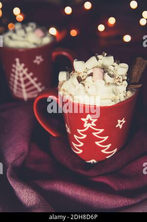 A creamy hot chocolate drink in a Christmas cup with whipped cream, chocolate and marshmallows with copy space Stock Photo