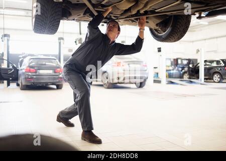 Young mechanic working under car in repair shop Stock Photo