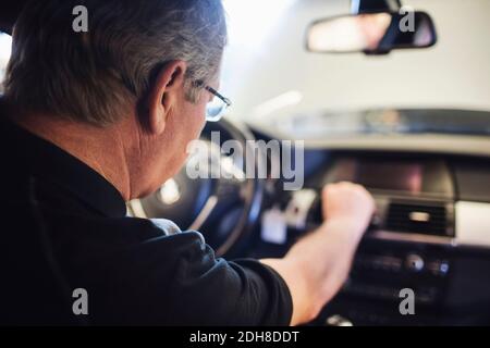 Close-up of senior mechanic examining air conditioner while sitting in car Stock Photo
