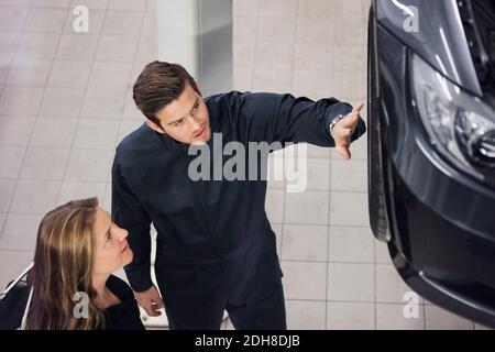 High angle view of young mechanic explaining to female customer at shop Stock Photo