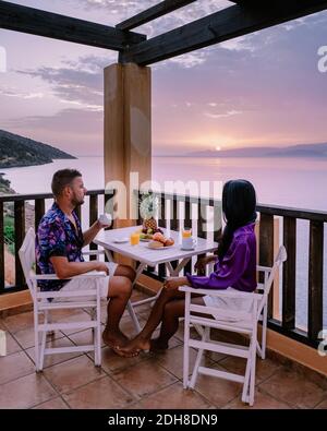 Table and chairs with breakfast during sunrise at the meditarian sea in Greece Stock Photo