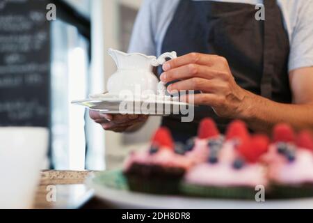 Midsection of man holding pitcher and plate at cafe Stock Photo