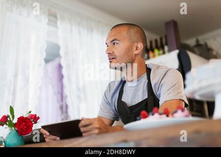 Male owner using digital tablet at cafe counter Stock Photo