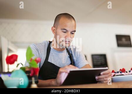 Male owner using digital tablet at cafe counter Stock Photo