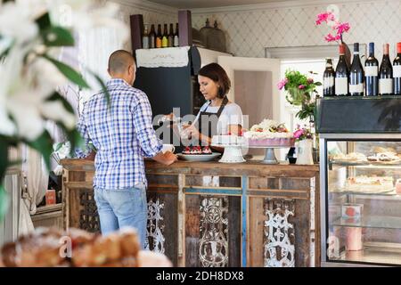 Female owner serving drink in glass for customer at counter in cafe Stock Photo