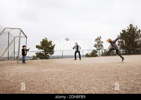 Teacher encouraging students while playing soccer on school playground Stock Photo