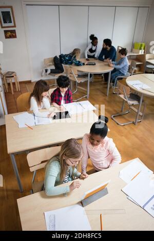 High angle view of students using digital tablet while sitting in classroom Stock Photo