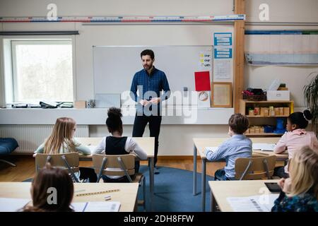 Confident teacher explaining students in classroom at school Stock Photo