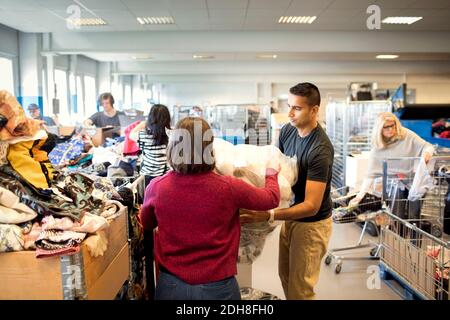 Man assisting woman in holding plastic while volunteers working at workshop Stock Photo