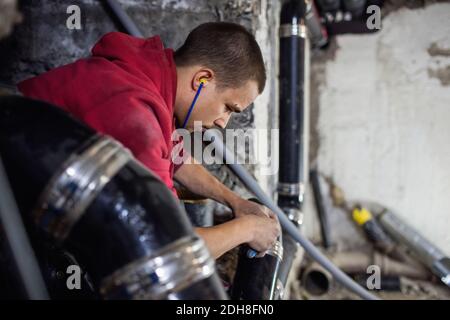 Concentrated plumber working on pipes while listening music in basement Stock Photo