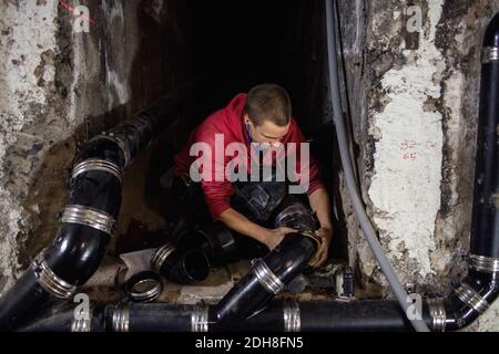 Concentrated plumber connecting pipes in basement Stock Photo