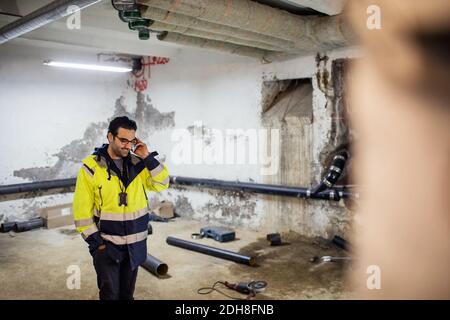 Smiling manual worker talking on phone in basement Stock Photo