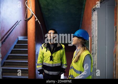 Female and male managers discussing while standing by steps at construction site Stock Photo