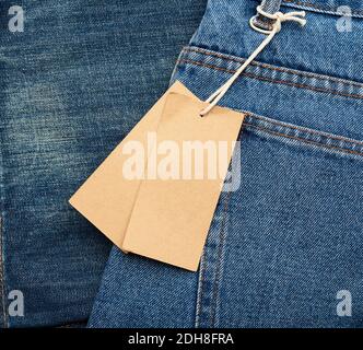 Blank brown rectangular tag tied in the back pocket of blue folded jeans Stock Photo
