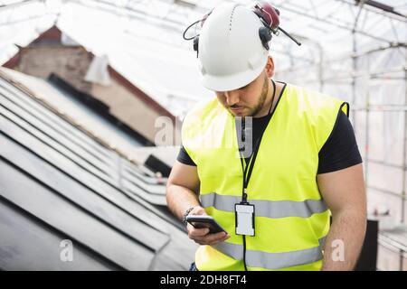 Manual worker using phone while working at construction site Stock Photo