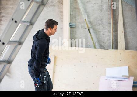 Concentrated manual worker looking at blue prints in construction site Stock Photo
