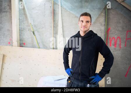 Confident manual worker standing with hands on hip at construction site Stock Photo