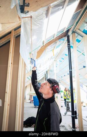 Side view of carpenter measuring height while working at site Stock Photo