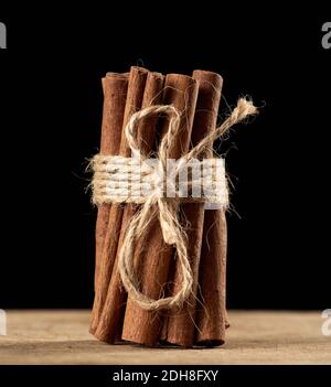 Tied bunch of brown cinnamon sticks on a brown wooden background Stock Photo