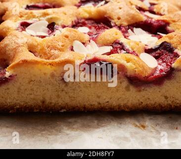 Baked slices of sponge cake with plums on brown paper and a knife Stock Photo