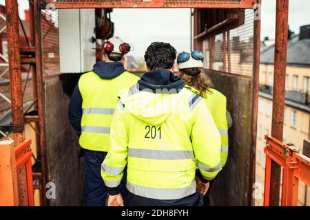 Rear view of construction workers standing in elevator at site Stock Photo