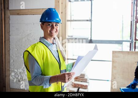 Portrait of confident female manual worker reading document at construction site Stock Photo