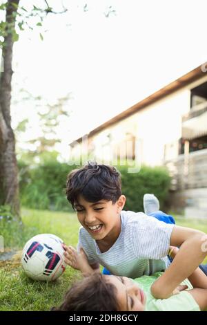 Playful boy lying at lawn against sky Stock Photo