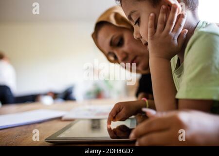 Side view of mother and son using digital tablet while studying at home Stock Photo