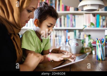 Mother and son using digital tablet at table Stock Photo