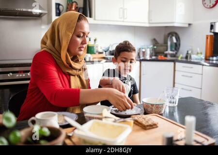 Mother and son having breakfast at dining table in kitchen Stock Photo