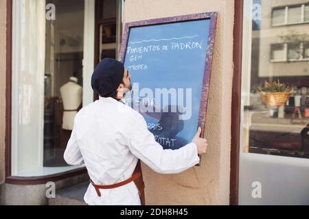 Male owner putting blackboard on wall outside grocery store Stock Photo