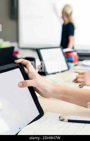 Cropped hand of girl using digital tablet at school Stock Photo