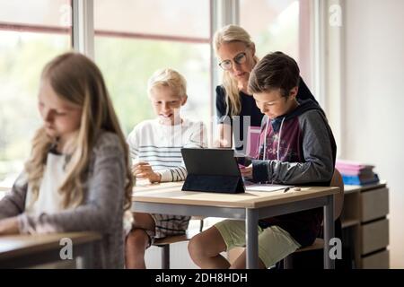 Teacher assisting children in e-learning from digital tablet Stock Photo