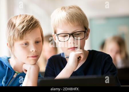 Boys using digital tablet for learning in classroom Stock Photo