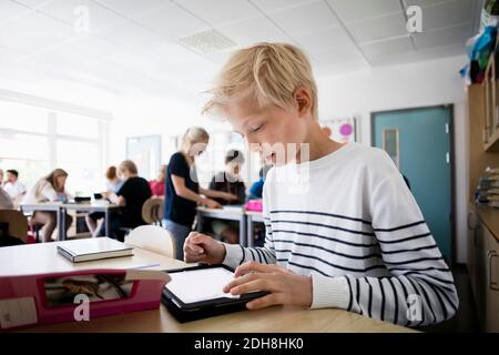 Boy using tablet pc at desk in classroom Stock Photo