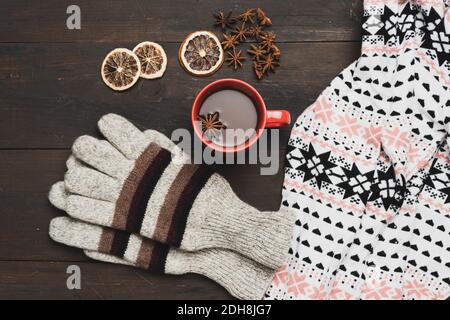 gray knitted mittens and red cup with a drink on a brown wooden table, top view Stock Photo