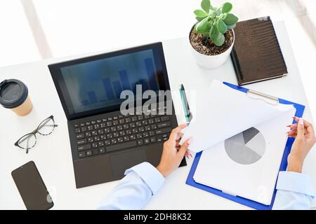 Top view of businesswoman analyzing financial reports sitting on modern white office desk Stock Photo