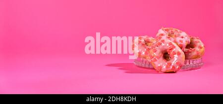 Sweet gift on Valentine's Day, Pink donuts with hearts on a bright background. Festive pastries. Long format banner. Copy space. High quality photo Stock Photo