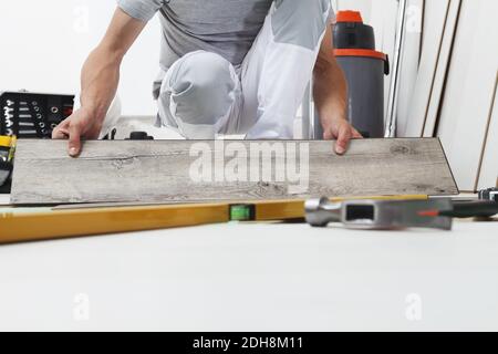 Worker hands installing timber laminate vinyl floor. Wooden floors house renovation. Stock Photo