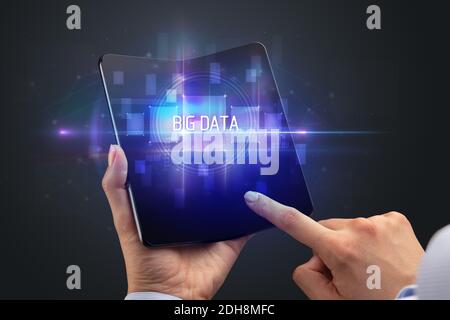 Businessman holding a foldable smartphone with BIG DATA inscription, new technology concept Stock Photo