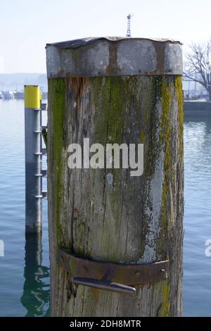 sea bollard standing in the water made of wood and rusty iron Stock Photo