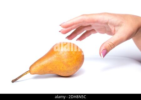 Womans hand picking ripe yellow pear, isolated on a white. Stock Photo